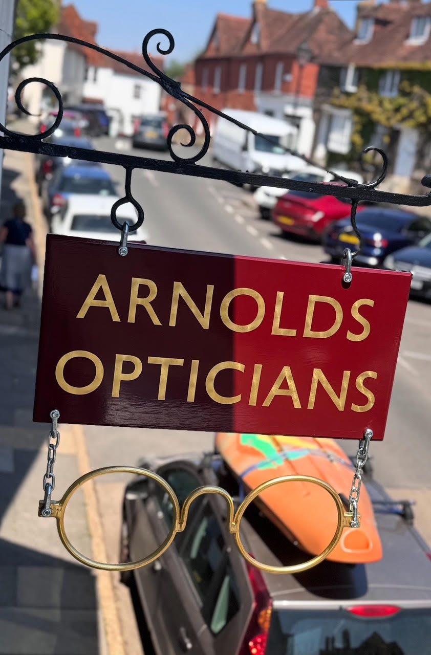 The gilt-and-claret bracket sign over Red Lion Street, round brass spectacles below.